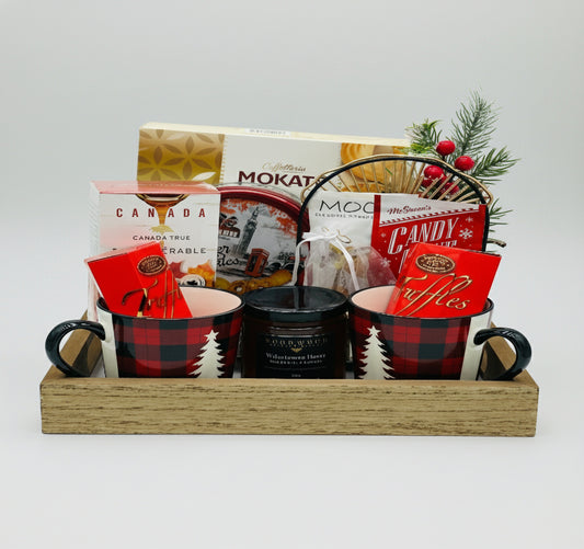 Gift basket with mugs, snacks, and a candle on a white background